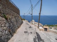 there is a stone wall that separates the street by the sea and two trucks are parked next to it