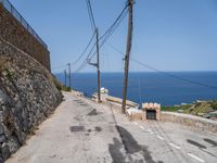 there is a stone wall that separates the street by the sea and two trucks are parked next to it