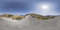 a panorama image of a long trail going up a hill and over a cliff side