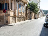 a motorcycle sits parked along a narrow road in the middle of town as people walk by