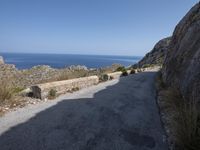 the view from a cliff, looking down a road with a lone biker on one side