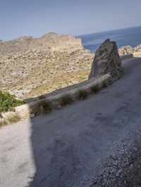 the man is riding his motorcyclist down a hill in the desert near the ocean