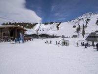 several skiers standing in front of the lodge on a snowy day, the lodge is covered with tall pines and snow
