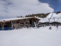 several skiers standing in front of the lodge on a snowy day, the lodge is covered with tall pines and snow