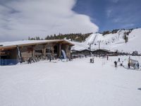 several skiers standing in front of the lodge on a snowy day, the lodge is covered with tall pines and snow