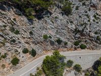 a man riding his bike down the road on a road surrounded by a mountain range