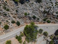 a man riding his bike down the road on a road surrounded by a mountain range