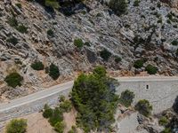 a man riding his bike down the road on a road surrounded by a mountain range