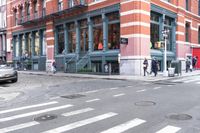 a man wearing a white shirt crossing the street in front of a red brick building