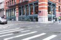 a man wearing a white shirt crossing the street in front of a red brick building