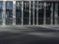 man crossing street in front of large glass building in urban area with gray pavement and street light