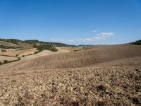 a man sitting on a grassy hill in a valley, with hills and trees in the distance