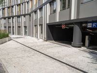 a man in black jacket on sidewalk next to building with parking signs in background and road going through garage area