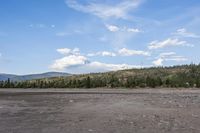 a man in a suit is standing by a horse on a dirt field near mountains