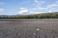 a man in a suit is standing by a horse on a dirt field near mountains
