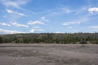 a man in a suit is standing by a horse on a dirt field near mountains
