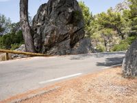 a lone man on a mountain road, with trees in the background of it, at the edge of a cliff