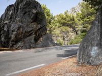 a lone man on a mountain road, with trees in the background of it, at the edge of a cliff