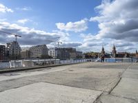 a man on a city waterfront with buildings behind him and one person walking away from the other