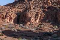 a man on a horse in the middle of a mountain range in front of a rock formation