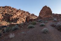 a man on a horse in the middle of a mountain range in front of a rock formation