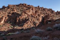 a man on a horse in the middle of a mountain range in front of a rock formation