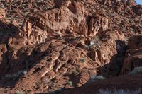 a man on a horse in the middle of a mountain range in front of a rock formation