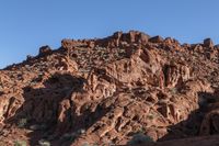 a man on a horse in the middle of a mountain range in front of a rock formation