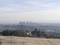 a man on top of a hill overlooking an urban setting with a city in the distance