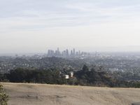 a man on top of a hill overlooking an urban setting with a city in the distance