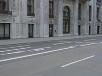 a man wearing a helmet and holding a red frisbee crossing the street in front of a building