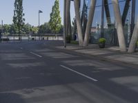 a man on a red skateboard rides by a building by the water near trees