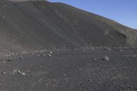 a man riding a red bicycle past a hill of rocks and gravels on a desert road