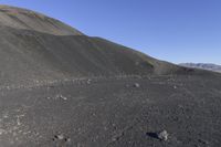 a man riding a red bicycle past a hill of rocks and gravels on a desert road