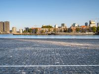 the man is riding his bike near the city with buildings in the background and a lake behind him