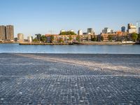 the man is riding his bike near the city with buildings in the background and a lake behind him