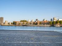 the man is riding his bike near the city with buildings in the background and a lake behind him