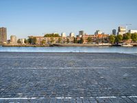 the man is riding his bike near the city with buildings in the background and a lake behind him