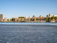 the man is riding his bike near the city with buildings in the background and a lake behind him