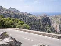 a man riding a bike down the road on top of a mountain side overlooking a rocky cliff
