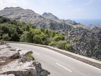 a man riding a bike down the road on top of a mountain side overlooking a rocky cliff