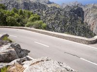a man riding a bike down the road on top of a mountain side overlooking a rocky cliff