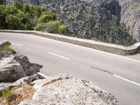 a man riding a bike down the road on top of a mountain side overlooking a rocky cliff