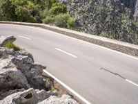 a man riding a bike down the road on top of a mountain side overlooking a rocky cliff