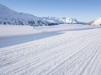 a man is riding his bike on a snowy path near mountains with snow and skis