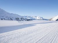 a man is riding his bike on a snowy path near mountains with snow and skis