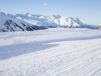 a man is riding his bike on a snowy path near mountains with snow and skis