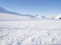 a man is riding his bike on a snowy path near mountains with snow and skis