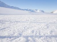 a man is riding his bike on a snowy path near mountains with snow and skis