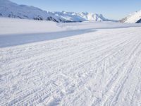 a man is riding his bike on a snowy path near mountains with snow and skis